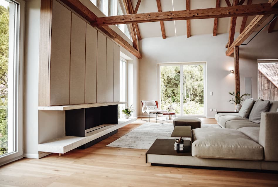 weiter Blick in den Wohnraum mit Couch, Lounge und Kamin Bereich - Schreinerei Würzburger München